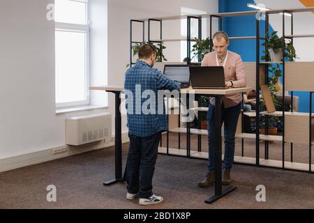 Deux CODEURS INFORMATIQUES travaillant sur l'ordinateur portable debout à la table au bureau Banque D'Images