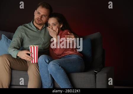 Portrait de jeune couple regardant un film d'horreur dans la salle sombre, se concentrer sur une jeune femme effrayée, espace de copie Banque D'Images