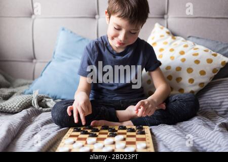 Les jeunes enfants jouent à des jeux de table sur le lit. Concept de quarantaine pour rester à la maison. Jeu de société et concept de loisirs pour enfants. Heure de la famille. Banque D'Images