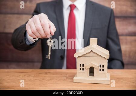 Un concept d'un homme d'affaires tel qu'un fournisseur d'hypothèques ou un agent immobilier qui remet les clés d'une maison ou d'une maison à de nouveaux propriétaires Banque D'Images