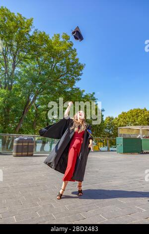 Jeune femme diplômée à Londres, qui célèbre son obtention d'un diplôme en univeresity en lançant son plateau de mortier à la haute des airs Banque D'Images