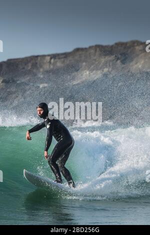 Un surfeur mâle d'âge mûr qui monte une vague à Fistral à Newquay, en Cornwall. Banque D'Images