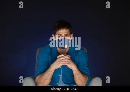 Portrait d'un homme barbu portant un masque tout en regardant un film à la maison en quarantaine, copier l'espace Banque D'Images