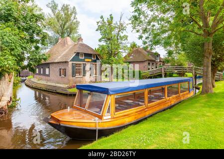 Bateau de croisière sur les canaux vide devant de vieilles maisons dans le village néerlandais de Giethoorn Banque D'Images