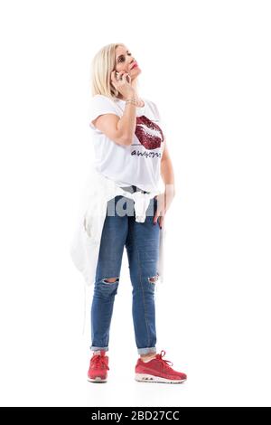 Sérieuse pensive inquiété femme d'âge moyen ou mère parler sur le téléphone portable à la recherche. Longueur totale du corps isolée sur fond blanc. Banque D'Images