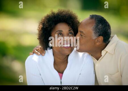 Un homme mûr heureux donne à sa femme souriante un baiser sur la joue. Banque D'Images