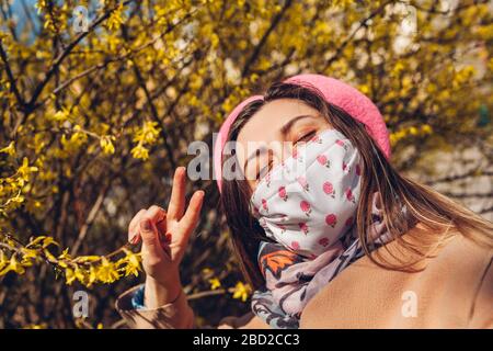 La femme porte un masque réutilisable à l'extérieur pendant la pandémie de covid-19 du coronavirus. Fille prend selfie avec des fleurs. Restez en sécurité Banque D'Images