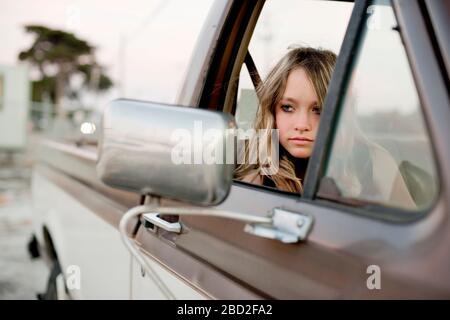 Jeune fille qui s'affine de la fenêtre dans le siège passager d'un camion de ramassage. Banque D'Images