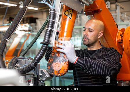 Ingénieur optimisant la production par bras robotisé dans l'usine automobile intelligente, employé dans l'industrie, concept industriel Banque D'Images