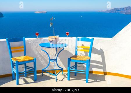 Grèce. Île de Thira. Paysage ensoleillé depuis un café d'Oia. Deux chaises et deux verres de vin Banque D'Images