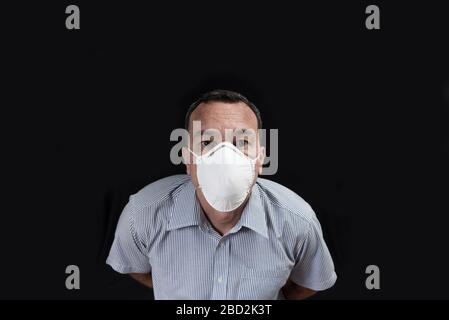 Homme masqué regardant directement l'objectif. Homme caucasien portant un masque respiratoire blanc Banque D'Images