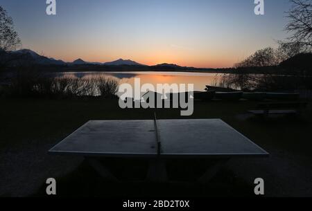 06 avril 2020, Bavière, Füssen: Une table de ping-pong se tient sur le bord du lac de Hop au coucher du soleil. Photo : Karl-Josef Hildenbrand/dpa Banque D'Images