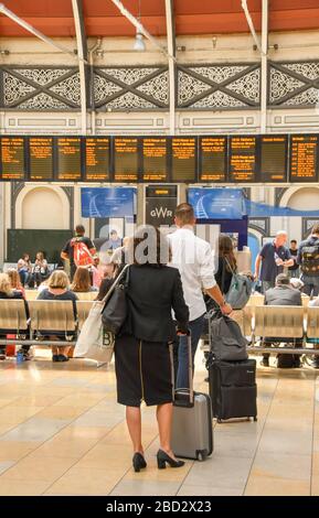 LONDRES, ANGLETERRE - JUILLET 2018 : voyageurs ferroviaires dans le hall de la gare de Paddington à Londres pour vérifier le panneau des départs électroniques Banque D'Images