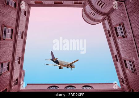 Un avion de passagers dans un beau ciel parmi des nuages spectaculaires vole au-dessus de la cour pendant le coucher du soleil. Maisons carrelées dans la ville de Porto au Portugal, en bas vi Banque D'Images