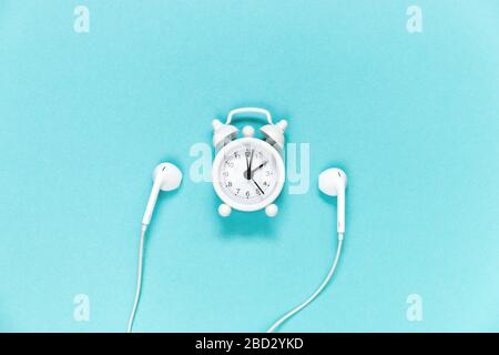 Casque et réveil sur fond bleu. Concept musical. Vue de dessus avec espace de copie. Banque D'Images