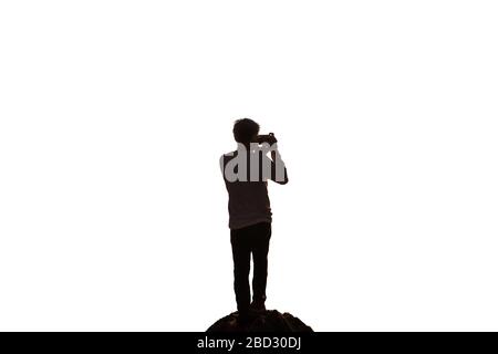 Silhouette homme voyageur debout avec la prise de photo d'un appareil photo rétro sur la roche. Isolé sur fond blanc Banque D'Images