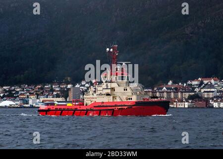 Un jour gris et pluvieux. Remorqueur BB Worker vient de terminer l'assistance d'un bateau de croisière au départ du port de Bergen, Norvège Banque D'Images