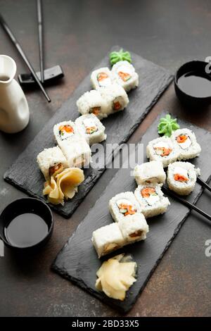 sushi pour deux. Kit pour deux avec baguettes, gingembre, soja, wasabi. Vue sur le fond en bois et les plaques d'ardoise noires. Banque D'Images