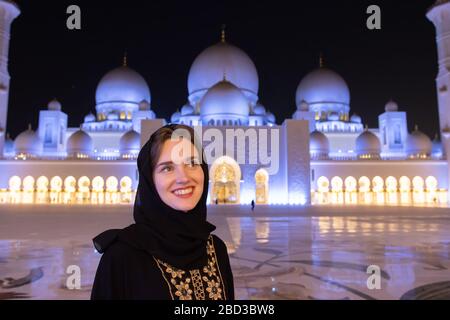 Abu Dhabi, Emirats Arabes Unis - 15 décembre 2019 : une jeune fille souriante admire la mosquée. Banque D'Images