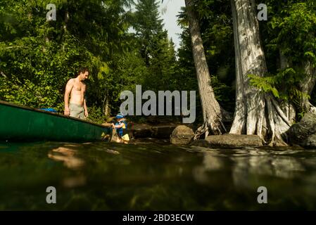 Une jeune fille marche à côté d'un canoë sur Lost Lake, en Oregon. Banque D'Images