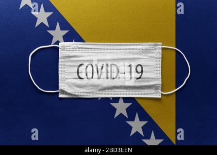 Un masque chirurgical médical individuel face sur le drapeau national de Bosnie-Herzégovine contexte. Masque de santé. Protection contre le virus COVID-19, grippe Banque D'Images