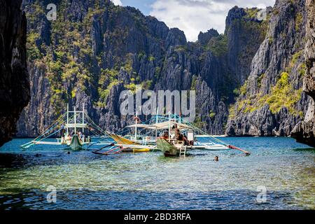 Bateaux de tourisme de la trémie de l'île dans un lagon encadré par des falaises à l'île Shimizu dans la baie de Bacuit près d'El Nido, Palawan, Philippines Banque D'Images