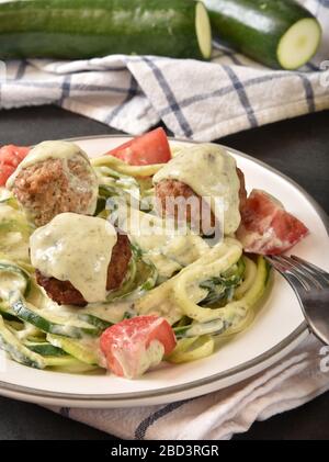 Un bol de pâtes courgettes spirales avec sauce au pesto de basilic Alfredo et boulettes de viande Banque D'Images