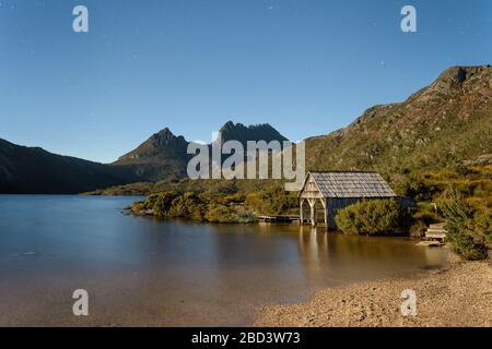 Des étoiles de l'heure bleue qui commencent à couvrir le légendaire lac Dove et le hangar de boatshed, menant aux deux pics de Cradle Mountain sur un ciel de nuit clair en Tasmanie. Banque D'Images