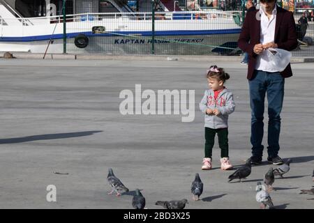 Le jeune homme marche sa petite sœur. Il alimente les pigeons. Filmé par temps clair et ensoleillé en hiver. Banque D'Images