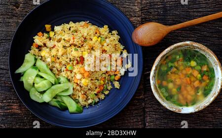 Femme vue haute main préparer la nourriture pour un dîner rapide, repas de Vegan avec riz pilaw frit, légumes de soupe comme carotte, maïs, plat végétarien vietnamien Banque D'Images
