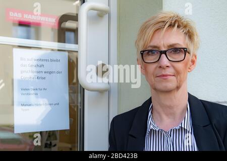 03 avril 2020, Basse-Saxe, Göttingen: Manuela Härtelt-Dören, maître de guilde d'état du commerce de coiffure en Basse-Saxe, est assis à l'entrée de son salon de coiffure à un signe disant "jusqu'à nouvel avis, le magasin restera fermé en raison de la crise de Corona". La fermeture ordonnée des magasins de coiffure est à l'origine de beaucoup d'entreprises en Basse-Saxe de grands problèmes. Photo: Swen Pförtner/dpa Banque D'Images