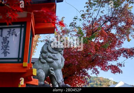 Statue de lion de pierre devant les portes du temple en automne Banque D'Images