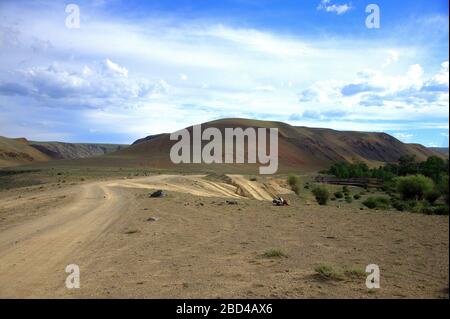 Une route de terre sinueuse et enveloppante de hautes collines traverse la vallée. Le tractus Chagan-Uzun, Altaï, Sibérie, Russie. Banque D'Images