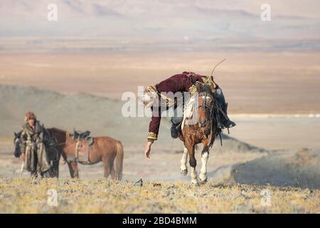 Jeu mongole traditionnelle où un cavalier sur l'objectif d'aller chercher une serviette depuis le sol à pleine vitesse au galop. Ulgii, la Mongolie. Banque D'Images