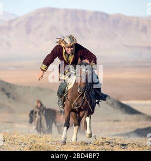 Jeu mongole traditionnelle où un cavalier sur l'objectif d'aller chercher une serviette depuis le sol à pleine vitesse au galop. Ulgii, la Mongolie. Banque D'Images