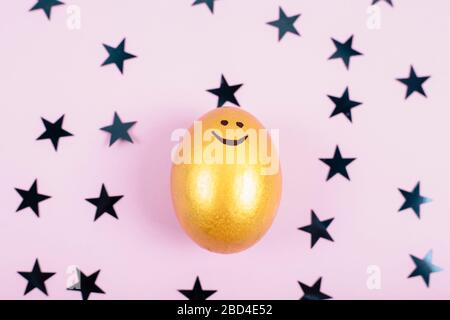 Joyeuses Pâques concept. Vue de dessus de l'oeuf de pâques coloré avec peinture dorée sur fond fastive avec étoiles. Espace de copie. Banque D'Images