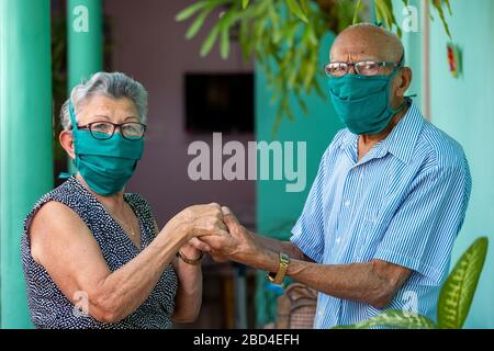 Couple âgé tenant les deux mains portant un masque facial Banque D'Images