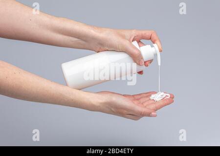 Les mains des blancs se lavant les unes les autres avec le savon de Marseille vert mousse isolé devant un fond gris avec des lumières et des ombres structurantes Banque D'Images