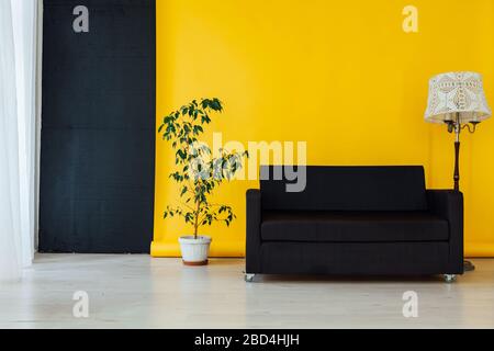 Canapé noir dans l'intérieur de la pièce avec un fond jaune Banque D'Images