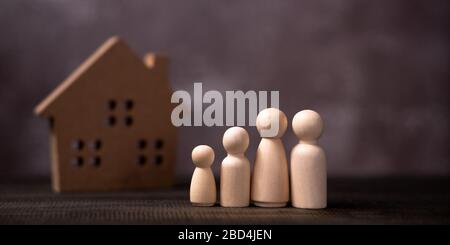 Famille de figurines en bois devant une maison en bois. Le concept de protection et de sécurité, de sécurité intérieure, d'assurance immobilière et de maison. Banque D'Images