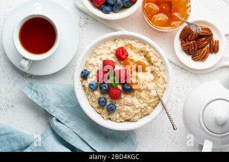 Porridge de flocons d'avoine avec bleuets, framboises, confiture et noix, vue de dessus. Petit déjeuner avec baies Banque D'Images