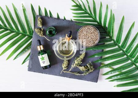 Bouteilles vertes d'huile médicale CBD avec graines de cannabis et bourgeons secs vue de dessus sur fond blanc. Extrait de cannabis médical. Médecine alternative co Banque D'Images