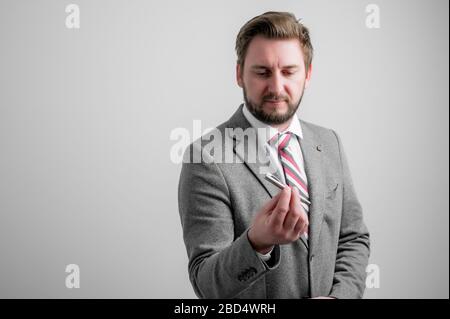 Portrait d'homme d'affaires portant des vêtements d'affaires montrant le stylo gris isolé sur fond gris avec espace de copie zone publicitaire Banque D'Images