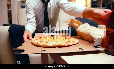 Homme d'affaires arrivant à la maison avec pizza après une longue journée au travail. Repos après travail. Banque D'Images