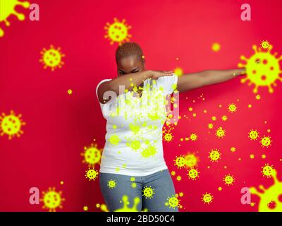 Comment éternuer droit - femme africaine abbing isolé sur fond de studio avec illustration de virus. Beau modèle féminin. Émotions humaines, ventes, santé et médecine concept. Arrêter l'épidémie. Banque D'Images
