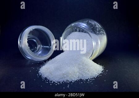 Sucre blanc dans un pot en verre ouvert macro gros plan sur fond noir photo image Banque D'Images