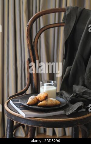 Petit-déjeuner avec quelques croissants et du lait servi sur une ancienne chaise dans la chambre Banque D'Images