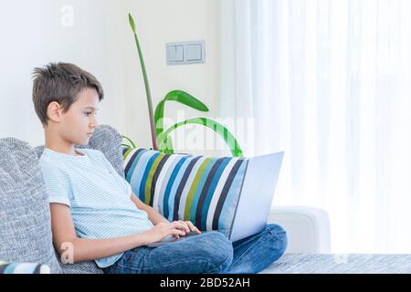 Préadolescent garçon utilisant l'ordinateur portable à la maison. Technologie, apprentissage en ligne, enseignement à distance, études à domicile, devoirs, jeux éducatifs pour enfants Banque D'Images