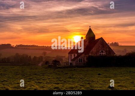 Coucher de soleil sur le parc national de South Downs à Idsworth avec l'église de St Hubert ioslated au premier plan Banque D'Images