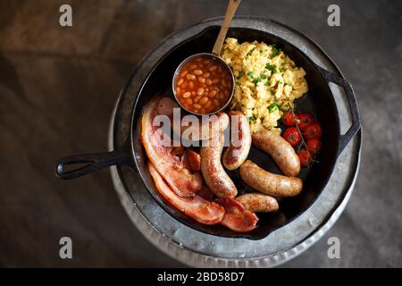 Un petit déjeuner traditionnel anglais complet dans une poêle sur fond sombre Banque D'Images